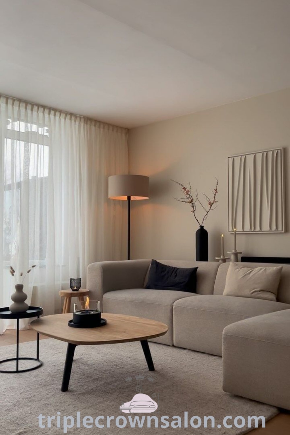 A minimal living room featuring a grey couch, coffee table, and a large window offering natural light. This design illustrates ideas for cozy home living, perfect for small contemporary living rooms. Discover more decor inspirations and tips for apartment living at triplecrownsalon.com.