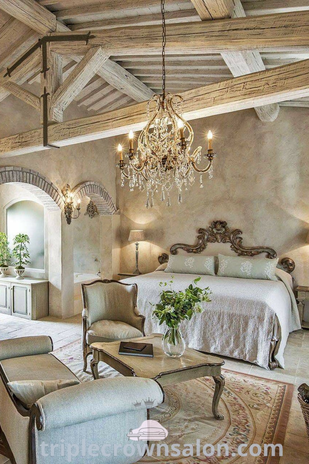 An elegant bedroom featuring a chandelier, bed, and stylish chairs, showcasing French Provincial style and cozy home ideas. This decor offers design tips for creating dreamy and romantic bedrooms. Find more decor ideas at triplecrownsalon.com.