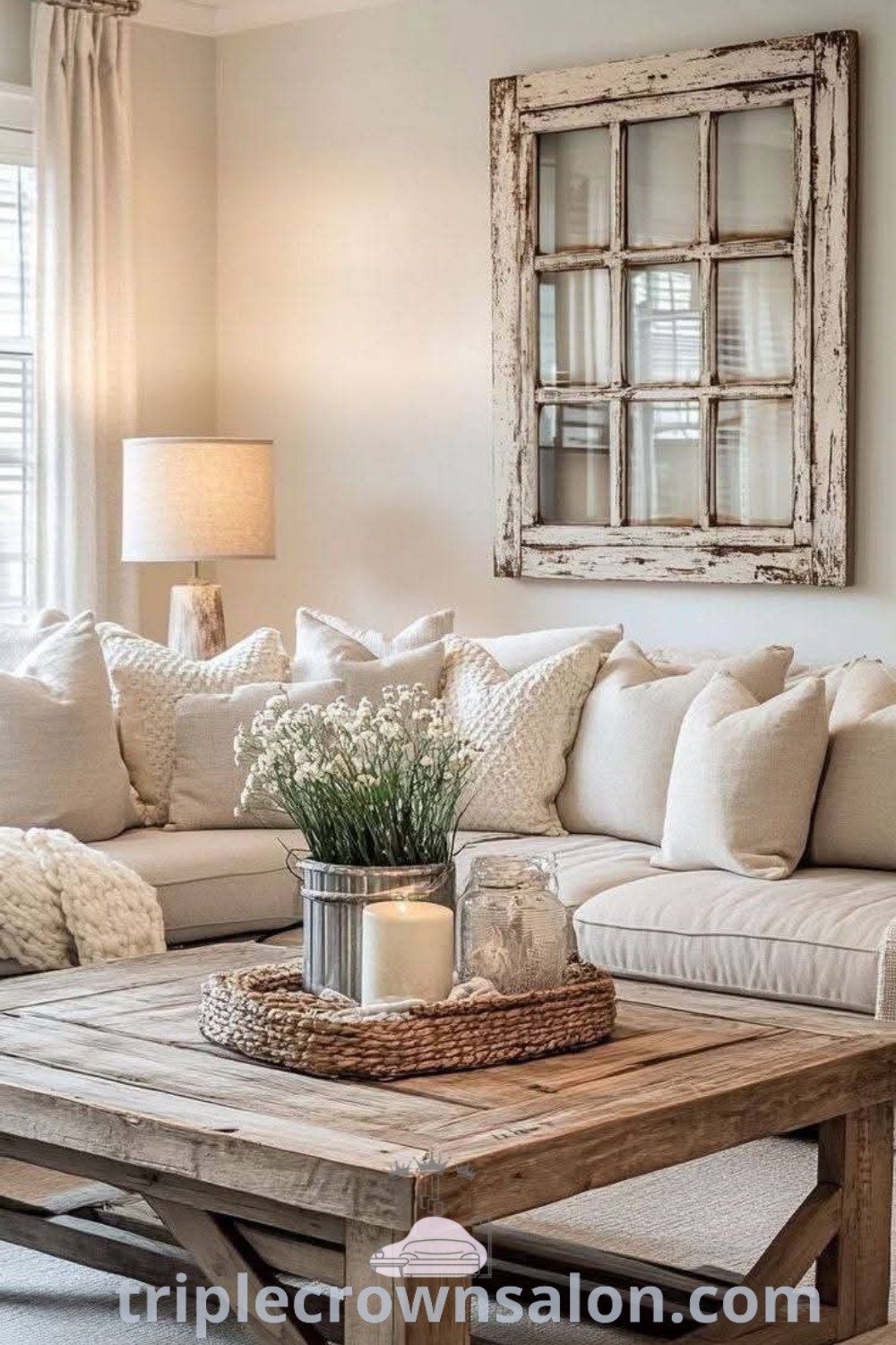 A cozy farmhouse living room featuring white couches and pillows on a table in front of a window. This space highlights rustic chic decor and comfortable aesthetics, offering unique ideas for decorating a cozy home. Discover more decor inspirations at triplecrownsalon.com.