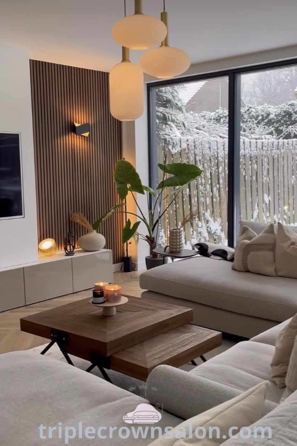 A modern living room with a cozy sofa, flat screen TV mounted on the wall, and stylish decor showcasing inspiring living room layout and design ideas for apartments. Explore more unique ideas for your home at triplecrownsalon.com.