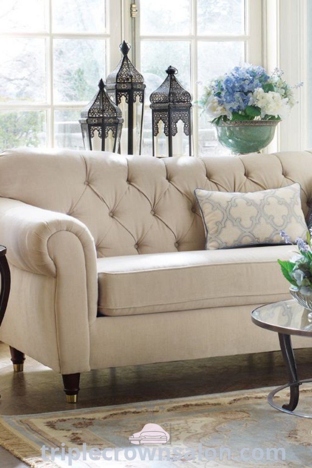 A cozy living room scene showcasing a traditional cream sofa and table arranged in front of a window, highlighting the charm of vintage sofas and offering decor ideas for a warm, inviting home. Find unique inspirations at wellnesswink.com.