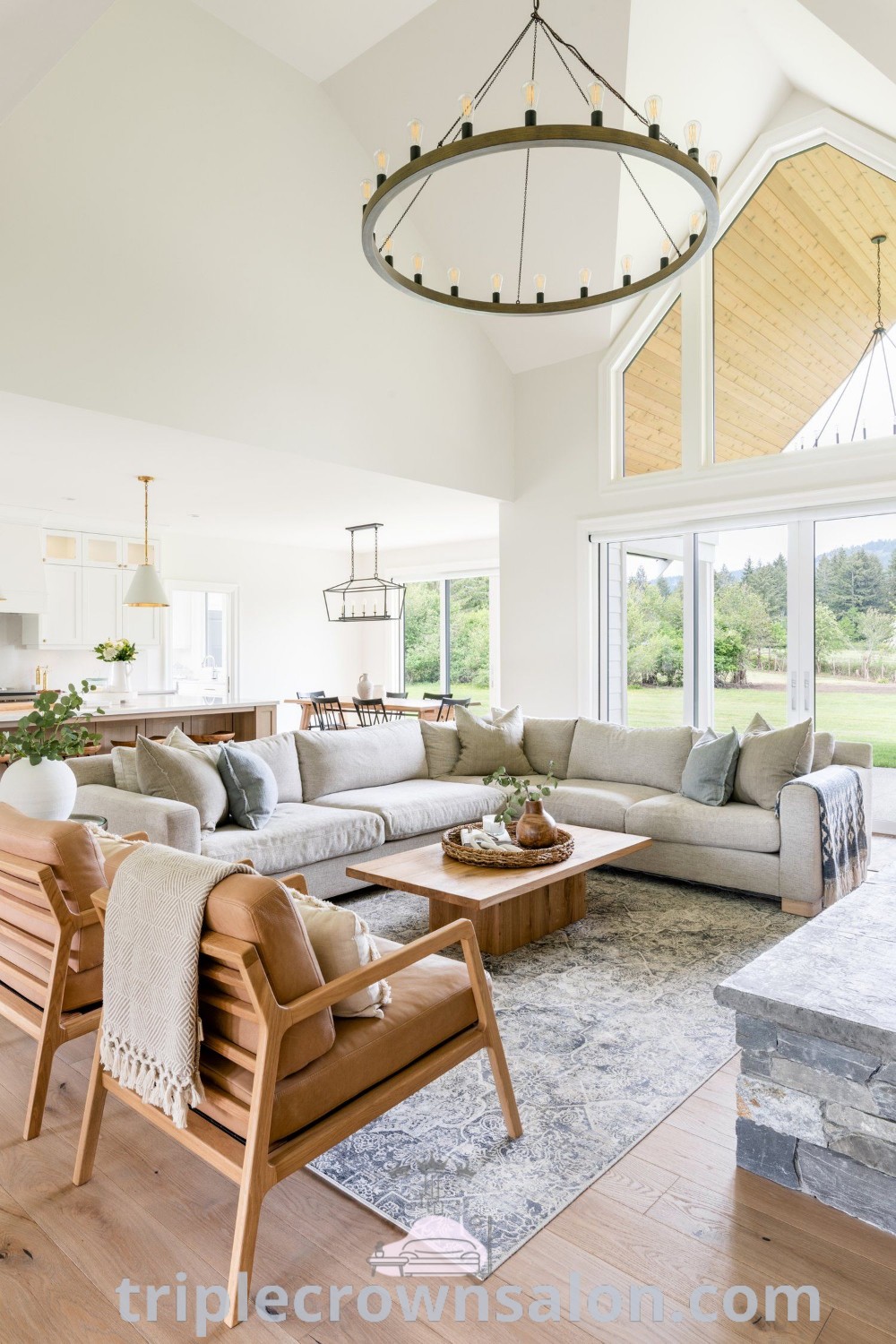 A bright modern farmhouse living room featuring a large open floor plan and wooden floors, filled with cozy furniture and decor ideas inspired by the modern farmhouse style. Discover unique ideas for creating a cozy home at triplecrownsalon.com.