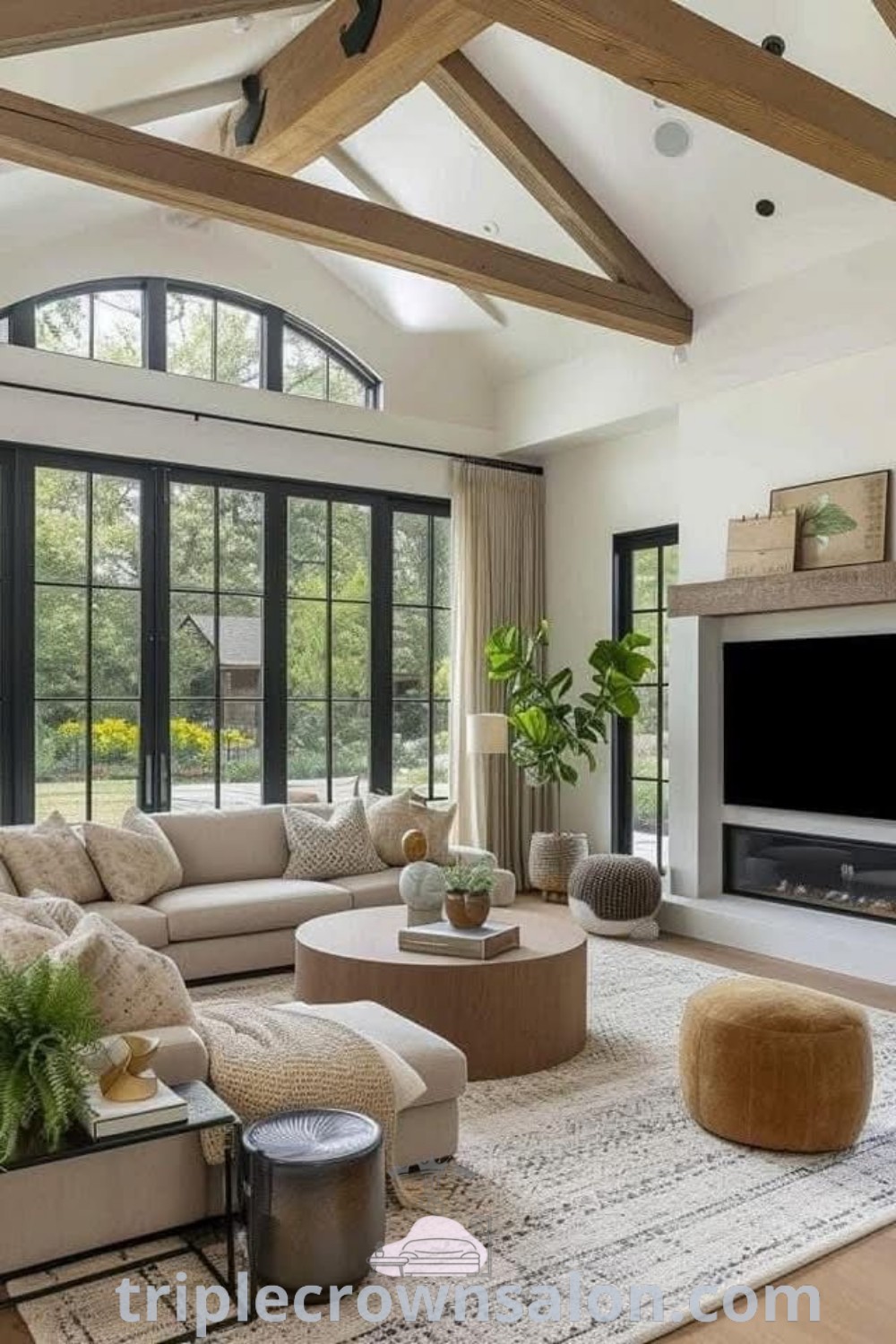 A cozy living room with a cathedral ceiling, stylish furniture, and a flat-screen TV over a fireplace, showcasing modern farmhouse living ideas and decor inspirations for a warm home atmosphere. Discover more design ideas at triplecrownsalon.com.