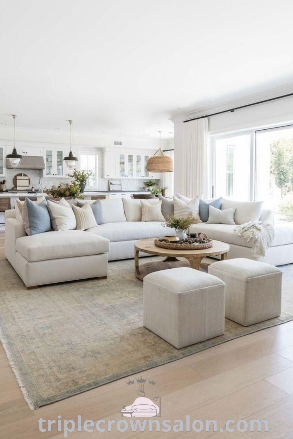A cozy coastal farmhouse living room featuring a large cream sectional couch, pillows, and a stylish rug that embodies inviting decor ideas for your home. This design showcases unique ideas for a cozy aesthetic and offers inspirations for small spaces. Explore more design tips at triplecrownsalon.com.