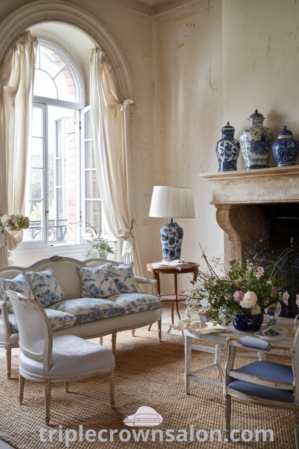 A cozy French aesthetic living room with a fireplace, large window, and chic furniture in regal blue and yellow accents, reflecting modern French provincial design trends. Discover inspiring decor ideas for small spaces and cozy home transformations at triplecrownsalon.com.