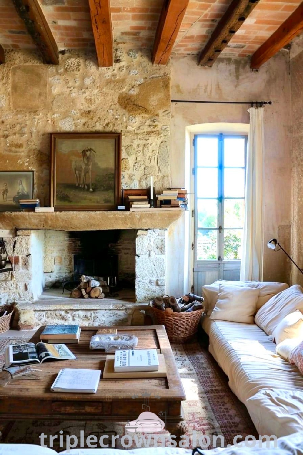 A cozy French country living room filled with comfortable furniture, a fireplace, and rustic decor. The space features an old brick wall and Tuscan design elements, showcasing inspiring ideas for your home. Discover more cozy home inspirations at triplecrownsalon.com.