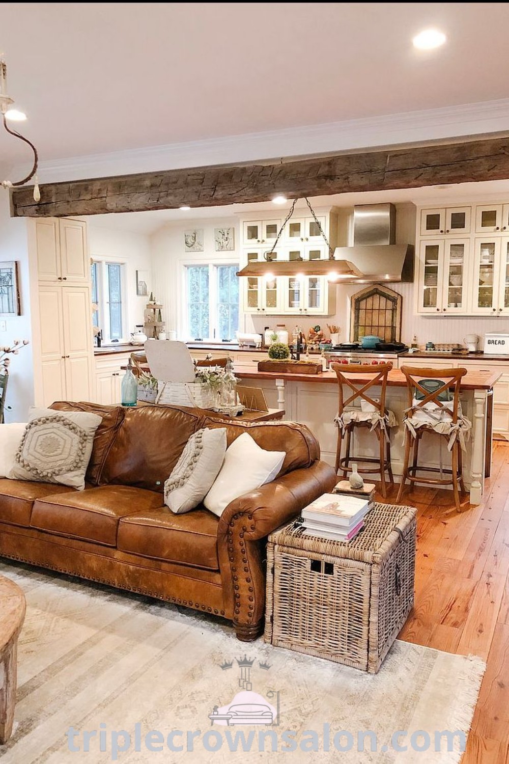 A charming farmhouse living room filled with stylish furniture, including a leather couch, next to a kitchen, offering inviting decor ideas and functional inspirations for a cozy home. Discover more design tips and unique ideas at triplecrownsalon.com.